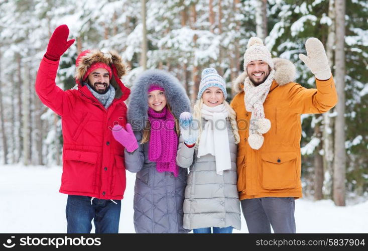 love, relationship, season, friendship and people concept - group of smiling men and women waving hands in winter forest