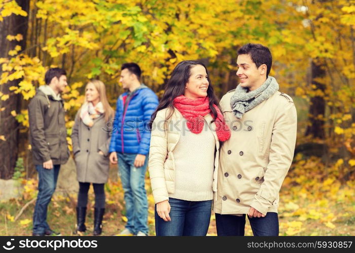 love, relationship, season, friendship and people concept - group of smiling men and women walking in autumn park