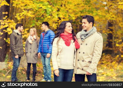 love, relationship, season, friendship and people concept - group of smiling men and women walking in autumn park