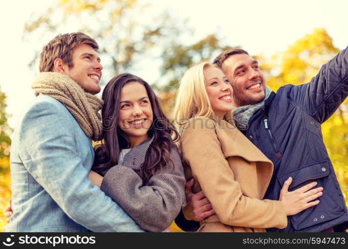 love, relationship, season, friendship and people concept - group of smiling men and women hugging in autumn park