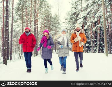 love, relationship, season, friendship and people concept - group of smiling men and women running in winter forest