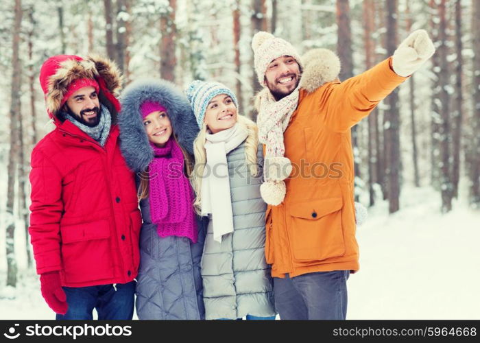 love, relationship, season, friendship and people concept - group of smiling men and women pointing finger in winter forest