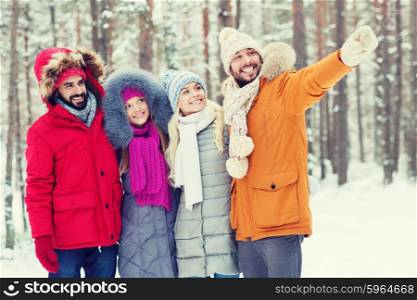 love, relationship, season, friendship and people concept - group of smiling men and women pointing finger in winter forest