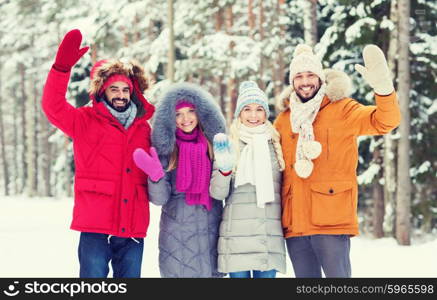 love, relationship, season, friendship and people concept - group of smiling men and women waving hands in winter forest