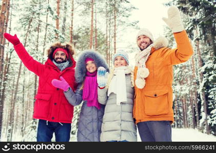 love, relationship, season, friendship and people concept - group of smiling men and women waving hands in winter forest