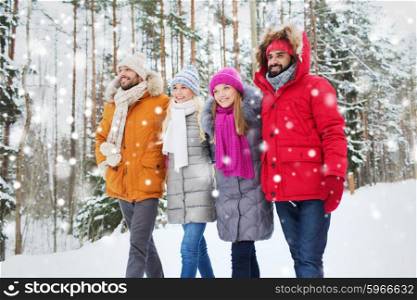 love, relationship, season, friendship and people concept - group of smiling men and women walking in winter forest. group of smiling men and women in winter forest