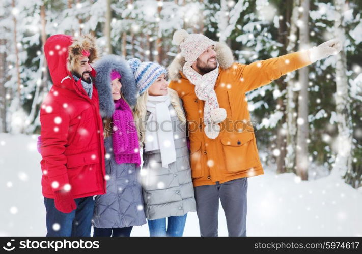 love, relationship, season, friendship and people concept - group of smiling men and women pointing finger in winter forest