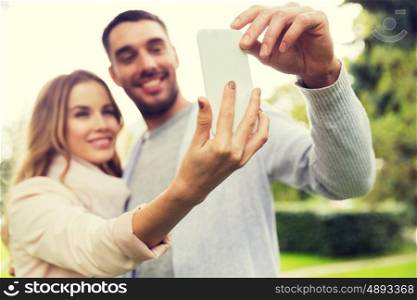 love, relationship, technology and people concept - close up of happy couple with smartphone taking selfie in summer park