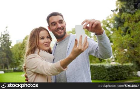 love, relationship, technology and people concept - happy couple with smartphone taking selfie in summer park