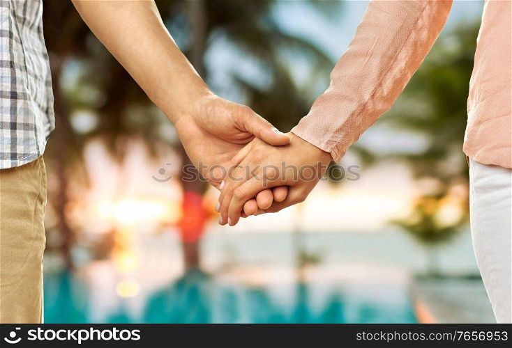 love, relationships and people concept - close up of happy couple holding hands over tropical beach background in french polynesia. close up of couple holding hands over exotic beach