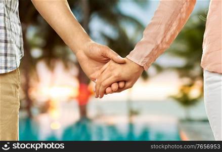 love, relationships and people concept - close up of happy couple holding hands over tropical beach background in french polynesia. close up of couple holding hands over exotic beach