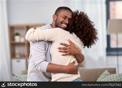 love, relationships and people concept - happy african american couple hugging at home. happy african american couple hugging at home