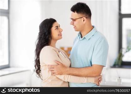 love, relationships and people concept - happy couple hugging and looking at each other at home. happy couple hugging at home