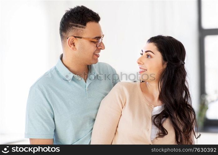 love, relationships and people concept - happy couple looking at each other at home. happy couple looking at each other at home