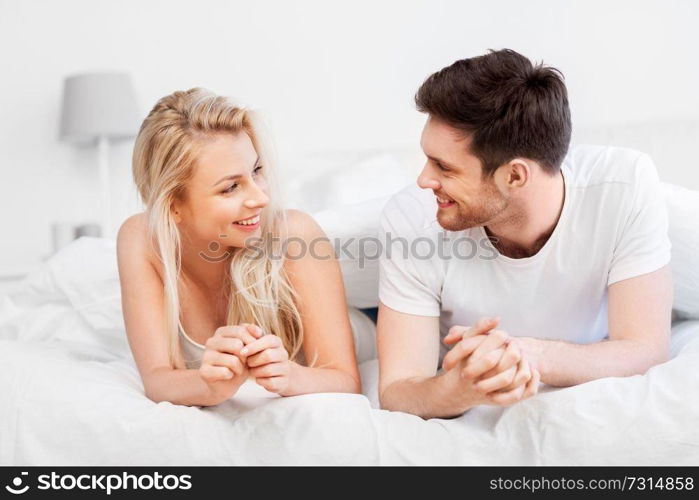 love, relationships and people concept - happy couple lying in bed at home. happy couple lying in bed at home
