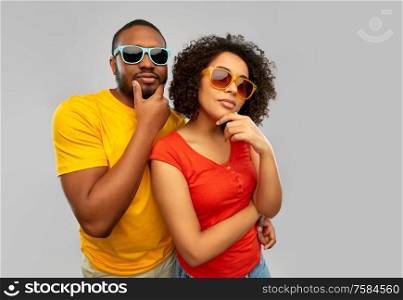 love, relationships and summer concept - african american couple in sunglasses thinking over grey background. african couple in sunglasses thinking