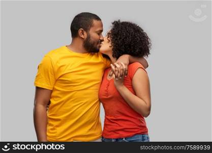 love, relationships and valentines day concept - happy african american couple kissing over grey background. happy african american couple kissing