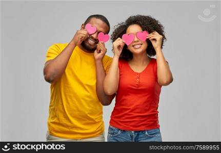 love, relationships and valentines day concept - happy african american couple with hearts having fun over grey background. happy african american couple with hearts