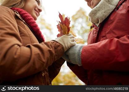 love, relationships, season and people concept - close up of happy couple with autumn maple leaves
