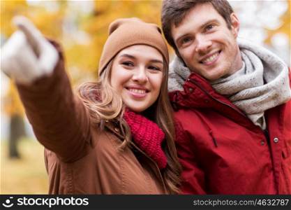 love, relationships, season and people concept - close up of happy young couple walking in autumn park