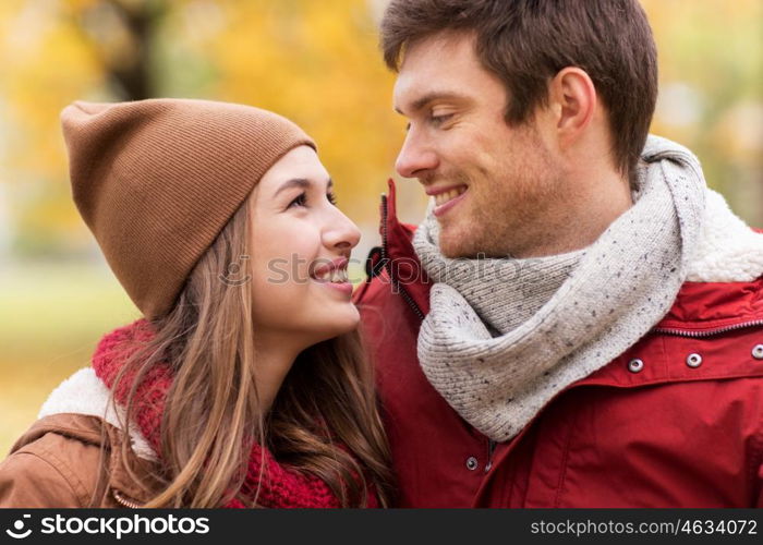 love, relationships, season and people concept - close up of happy young couple walking in autumn park and talking