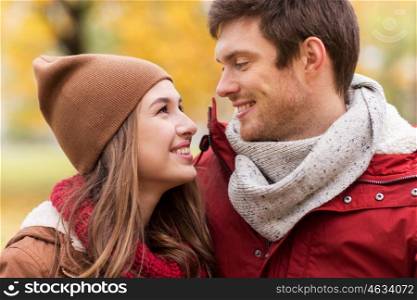 love, relationships, season and people concept - close up of happy young couple walking in autumn park and talking
