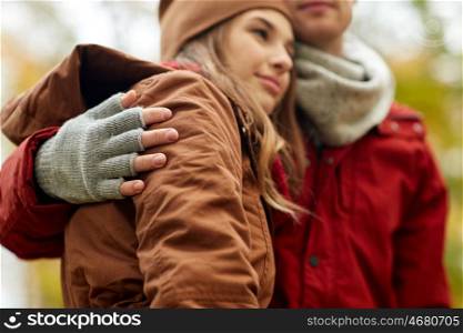 love, relationships, season and people concept - close up of happy young couple hugging in autumn park