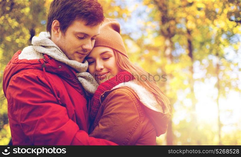 love, relationships, season and people concept - close up of happy young couple hugging in autumn park. close up of happy couple hugging in autumn park