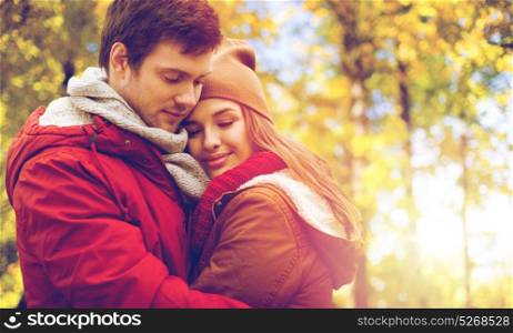 love, relationships, season and people concept - close up of happy young couple hugging in autumn park. close up of happy couple hugging in autumn park