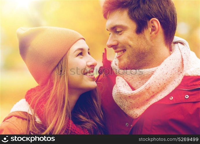 love, relationships, season and people concept - close up of happy young couple walking in autumn park and talking. close up of happy couple walking in autumn park