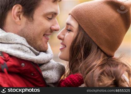 love, relationships, season and people concept - close up of happy young couple kissing outdoors