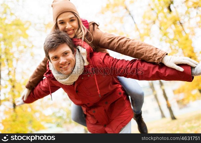 love, relationships, season and people concept - happy young couple having fun in autumn park