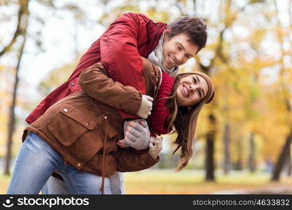 love, relationships, season and people concept - happy young couple having fun in autumn park