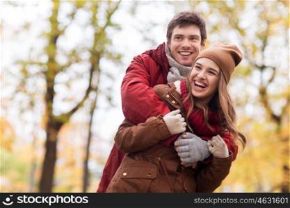 love, relationships, season and people concept - happy young couple hugging and laughing in autumn park