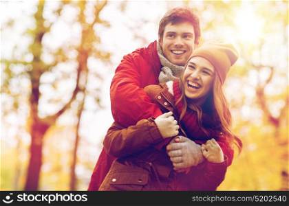 love, relationships, season and people concept - happy young couple hugging and laughing in autumn park. happy young couple hugging in autumn park