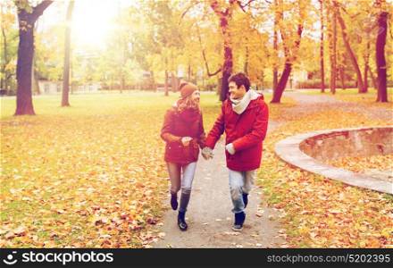 love, relationships, season and people concept - happy young couple running in autumn park and talking. happy young couple running in autumn park