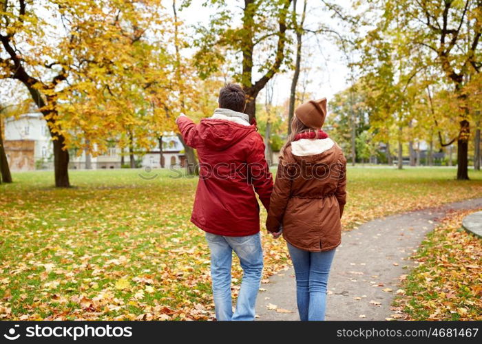 love, relationships, season and people concept - happy young couple walking in autumn park and pointing finger to something