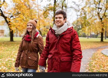 love, relationships, season and people concept - happy young couple walking in autumn park