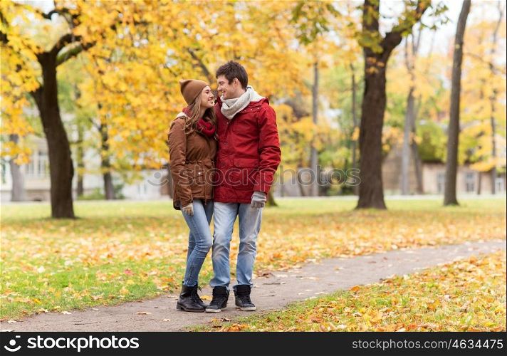 love, relationships, season and people concept - happy young couple walking in autumn park