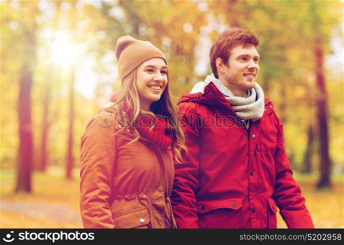 love, relationships, season and people concept - happy young couple walking in autumn park. happy young couple walking in autumn park