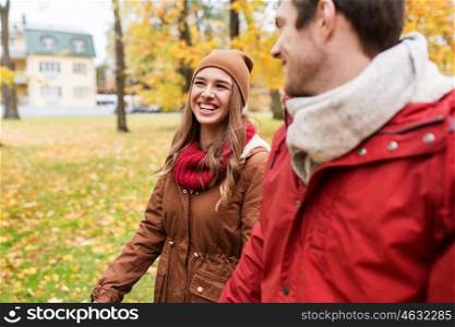 love, relationships, season and people concept - happy young couple walking in autumn park and talking