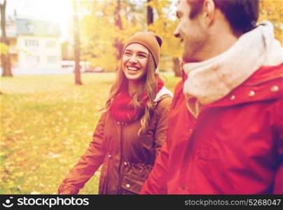 love, relationships, season and people concept - happy young couple walking in autumn park and talking. happy young couple walking in autumn park