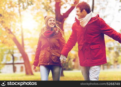 love, relationships, season and people concept - happy young couple walking in autumn park and talking. happy young couple walking in autumn park