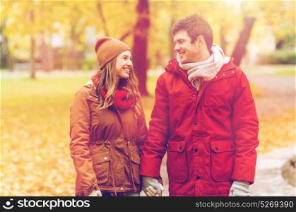 love, relationships, season and people concept - happy young couple walking in autumn park and talking. happy young couple walking in autumn park