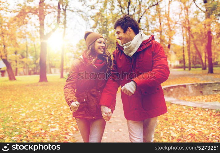 love, relationships, season and people concept - happy young couple walking in autumn park and talking. happy young couple walking in autumn park