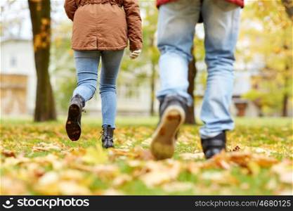 love, relationships, season and people concept - young couple running in autumn park