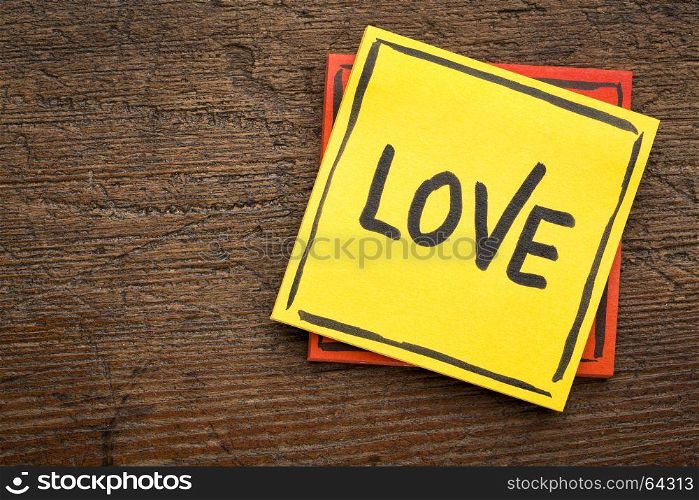 Love reminder - handwriting on a sticky note against rustic wood