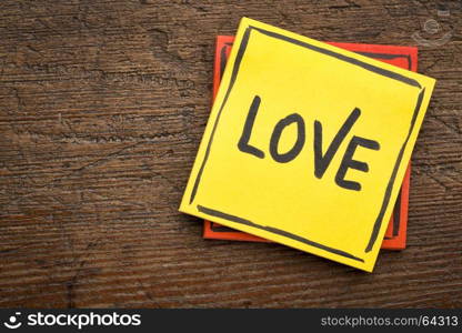 Love reminder - handwriting on a sticky note against rustic wood