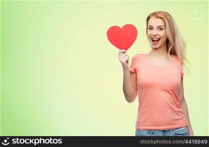 love, romance, charity, valentines day and people concept - smiling young woman or teenage girl with blank red heart shape over green natural background