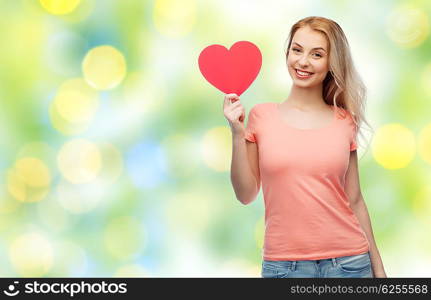love, romance, charity, valentines day and people concept - smiling young woman or teenage girl with blank red heart shape over summer green lights background